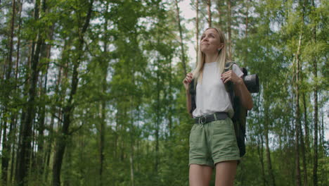 Slow-motion:-Adult-caucasian-woman-wearing-shorts-and-t-shirt-hikes-through-woods.-Female-hiker-with-backpack-walking